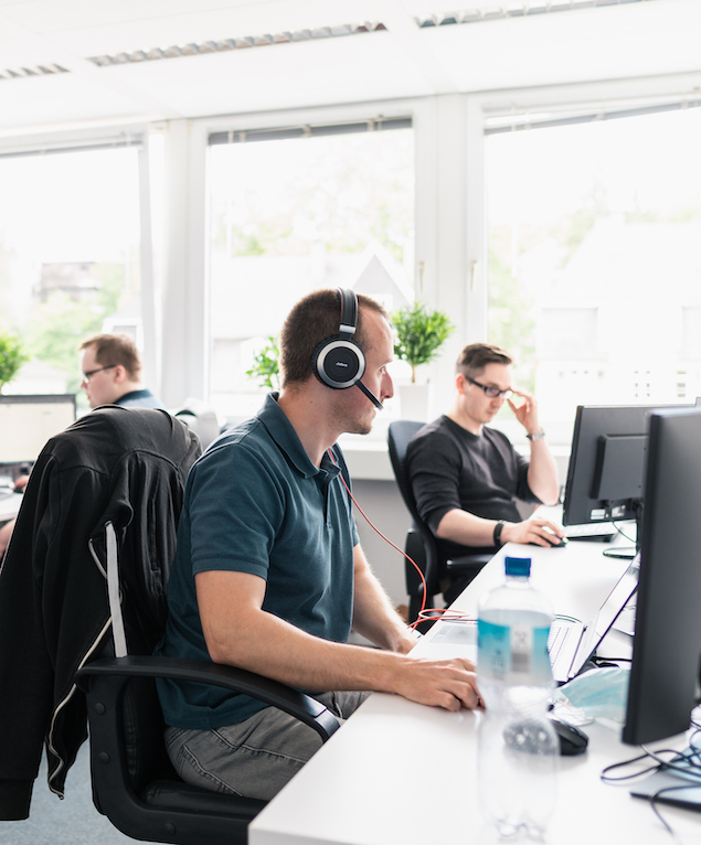 Drei Lorent IT Mitarbeiter an Schreibtischen vor PCs
