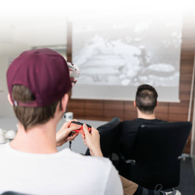 Lorent IT Mitarbeiter sitzen vor Leinwand und spielen Computerspiele